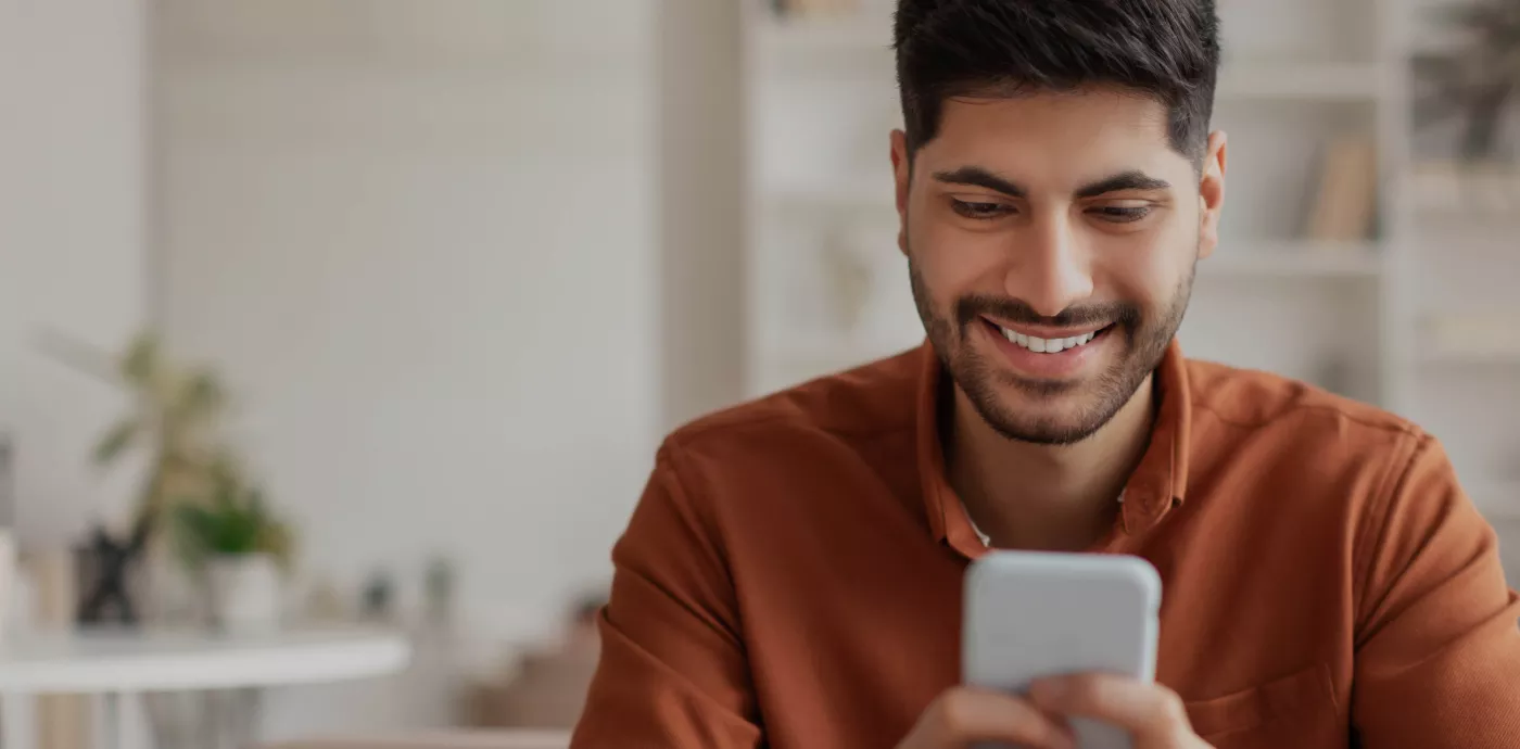 man smiling while looking at phone